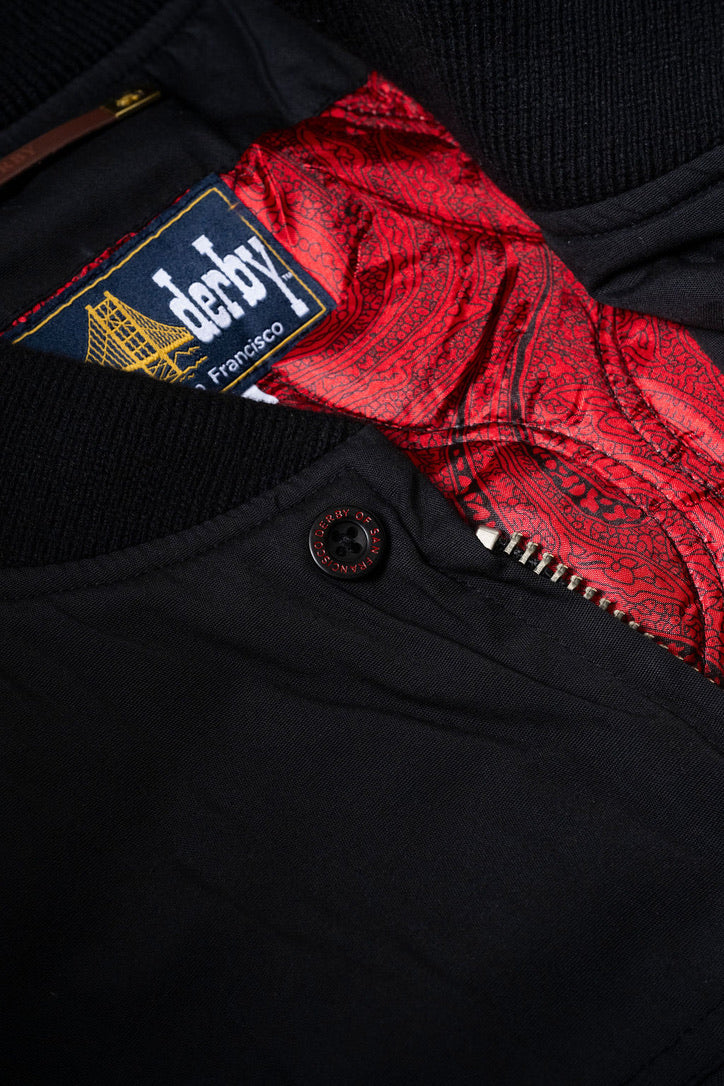 Black fabric with a red patterned fabric peeking out and a visible brand label.