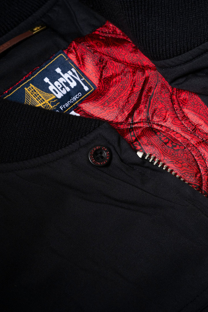 Black fabric with a red patterned fabric peeking out and a visible brand label.