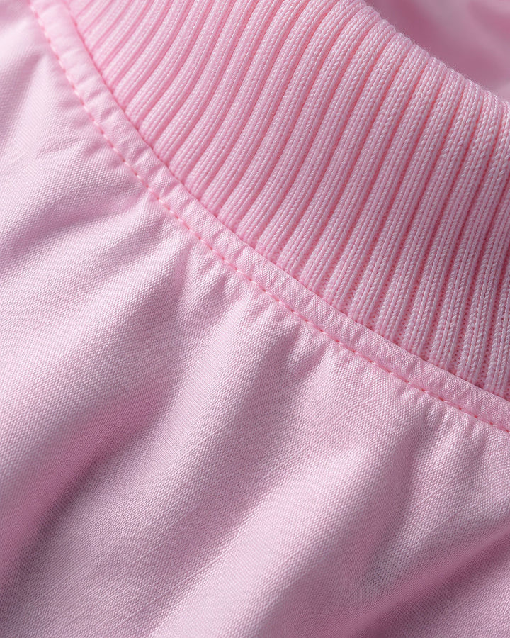 Close-up of a light pink garment showing a ribbed knit collar with fine stitching and smooth fabric below.
