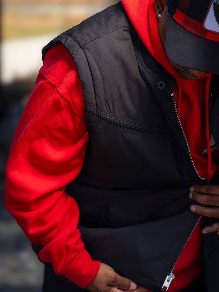 Person wearing a red jacket and black vest with a blurred background