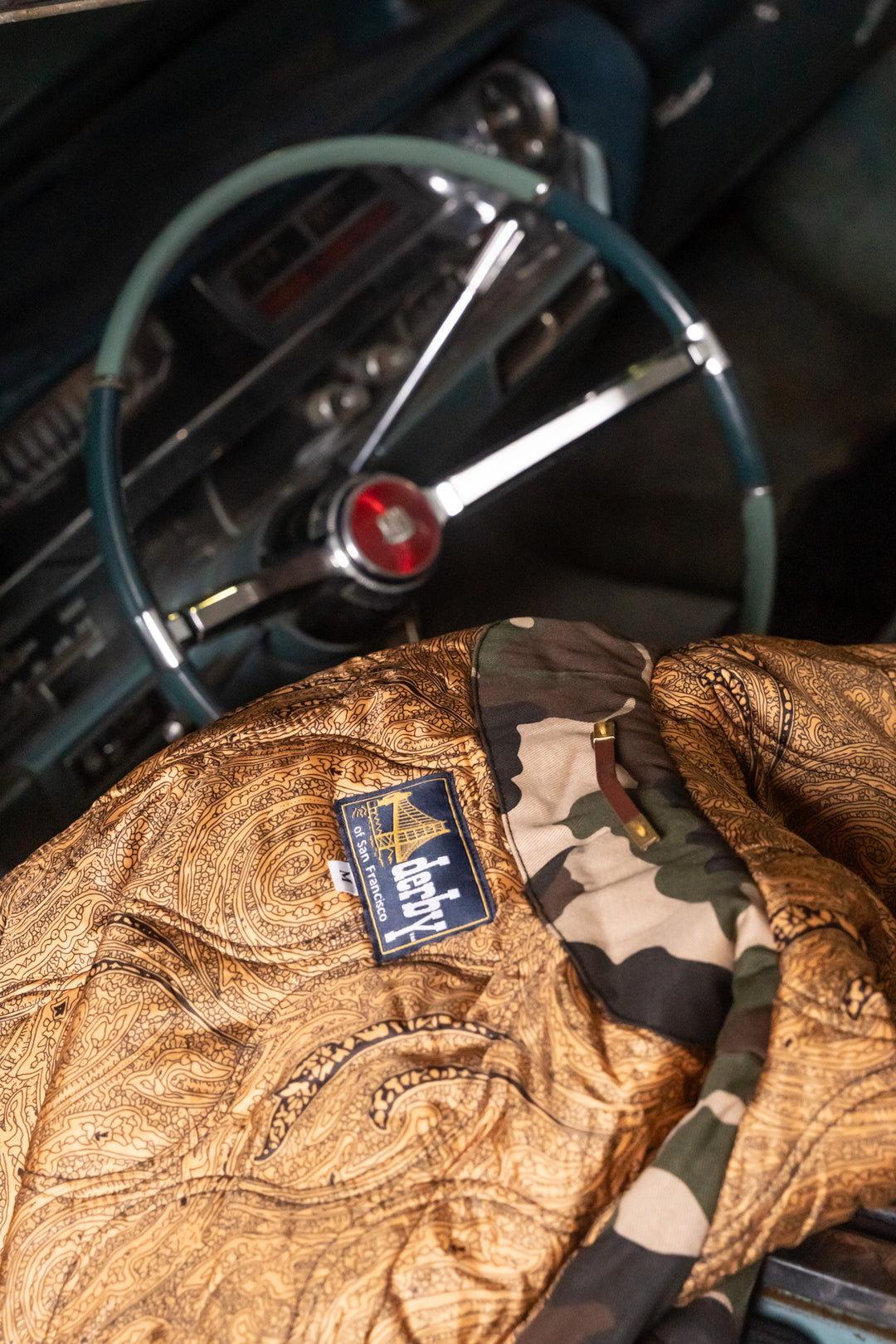 Close-up of a leather jacket with a brand logo in an old car interior.