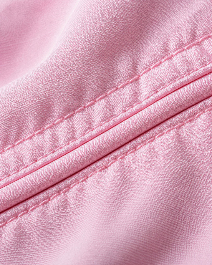 Close-up of light pink fabric with a diagonal stitched seam showing the texture and weave.
