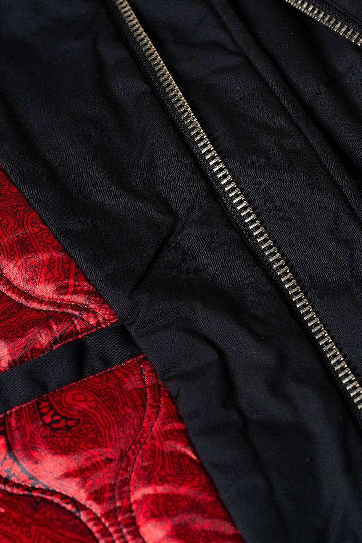 Close-up of a black jacket with a red patterned lining and zipper detail.