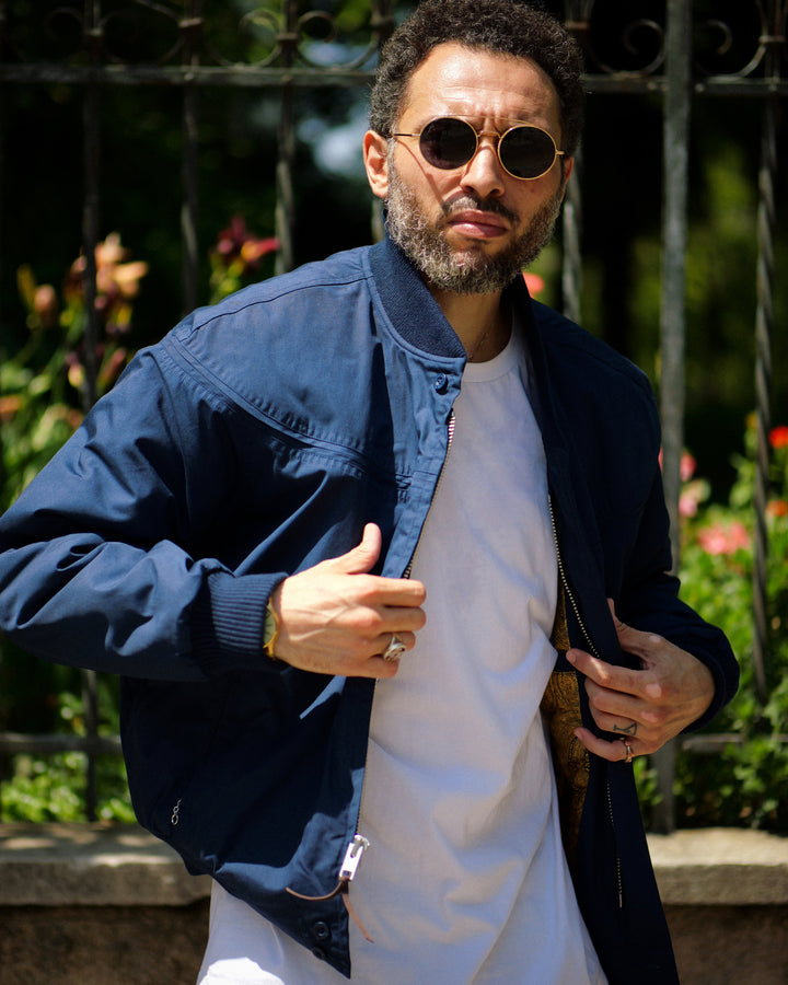 Man wearing sunglasses and a blue jacket with a blurred background