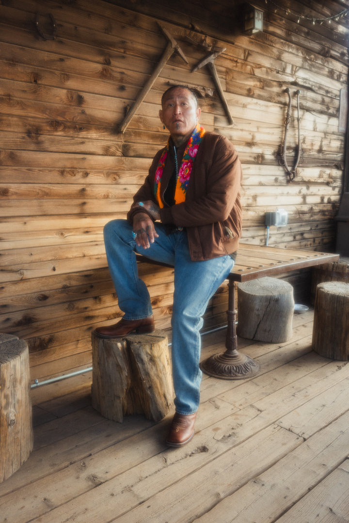 Man sitting on a wooden bench in a rustic interior setting.