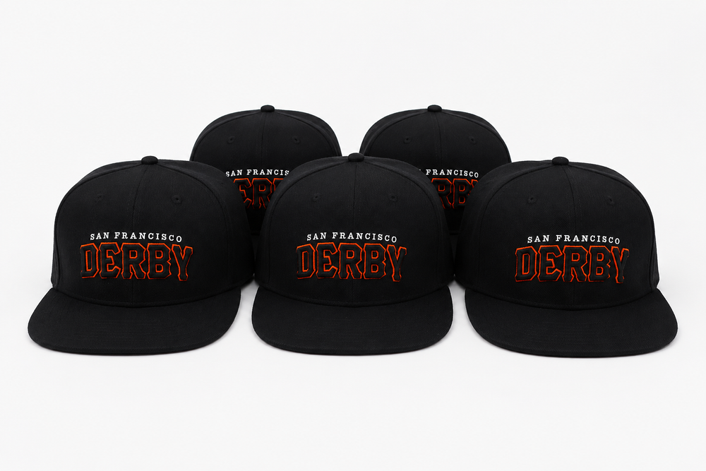 Five black flat-brim snapback caps arranged in a row on a light gray background. Each cap features embroidered text reading 'SAN FRANCISCO DERBY' in orange and white.
