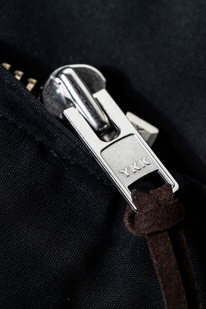 Close-up of a zipper pull on a black fabric background