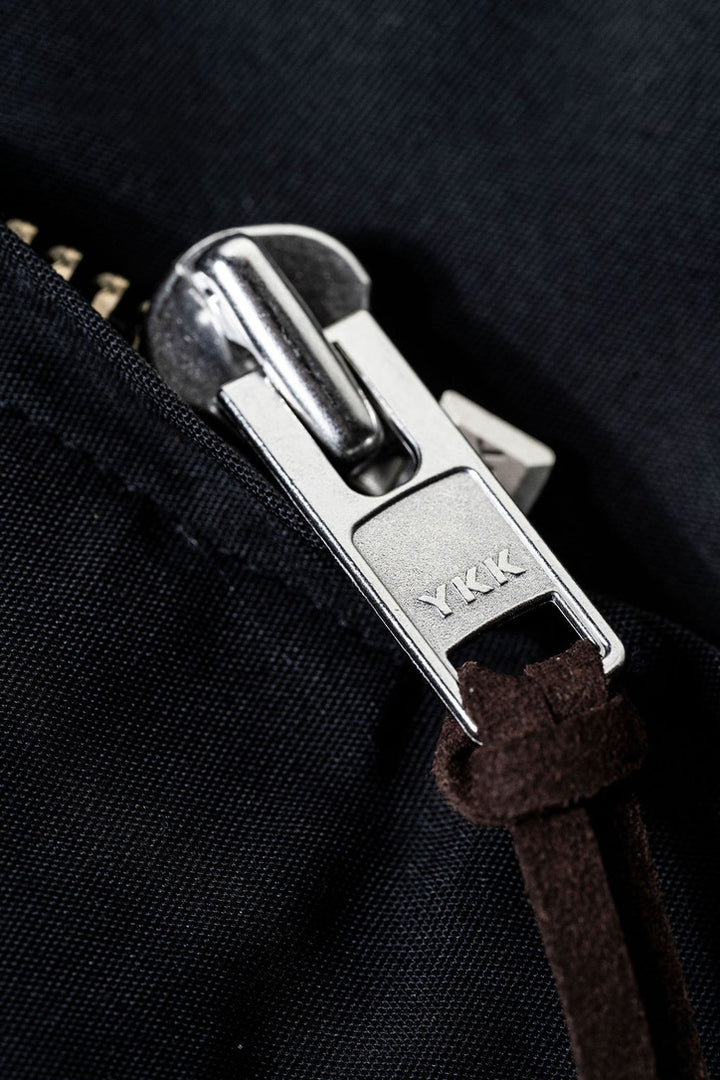 Close-up of a zipper pull on a black fabric background