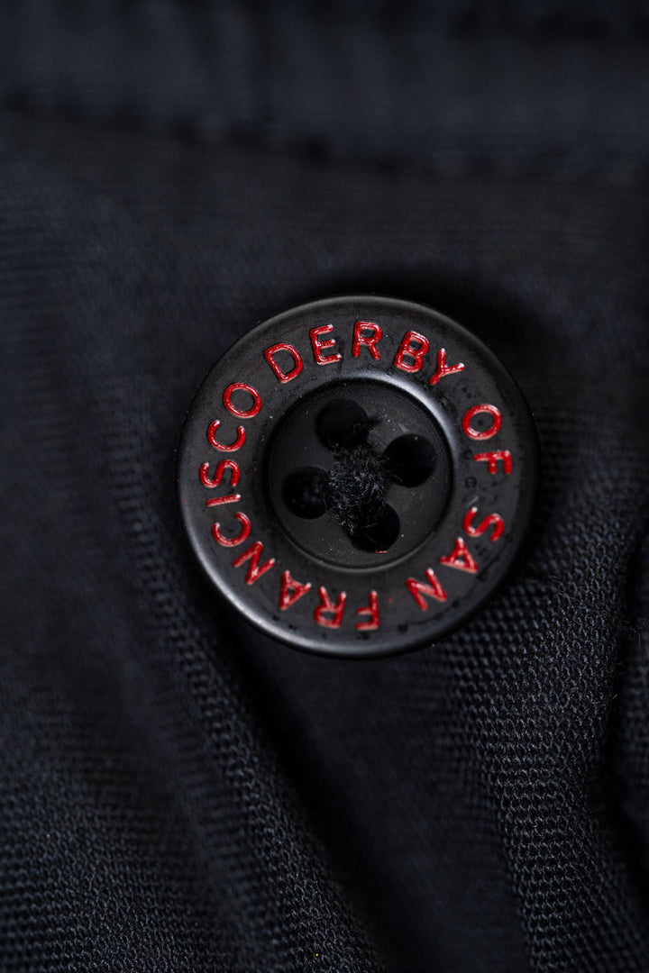 Black button with red text on a dark fabric background
